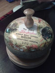 The Welsh Bonspiel trophy, made up of a painted curling stone mounted on a wooden plinth